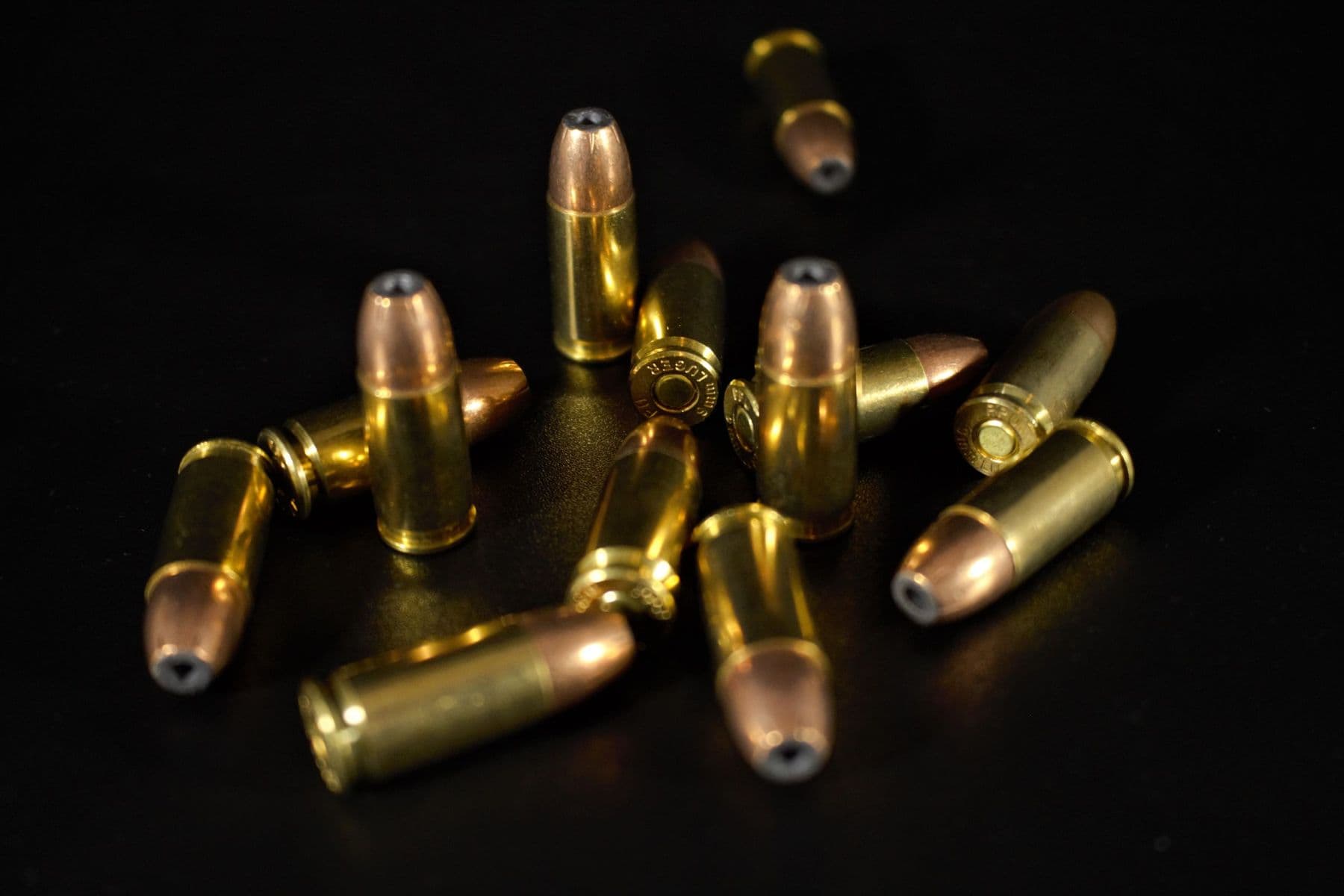 Hollow-point pistol bullets scattered on a dark surface