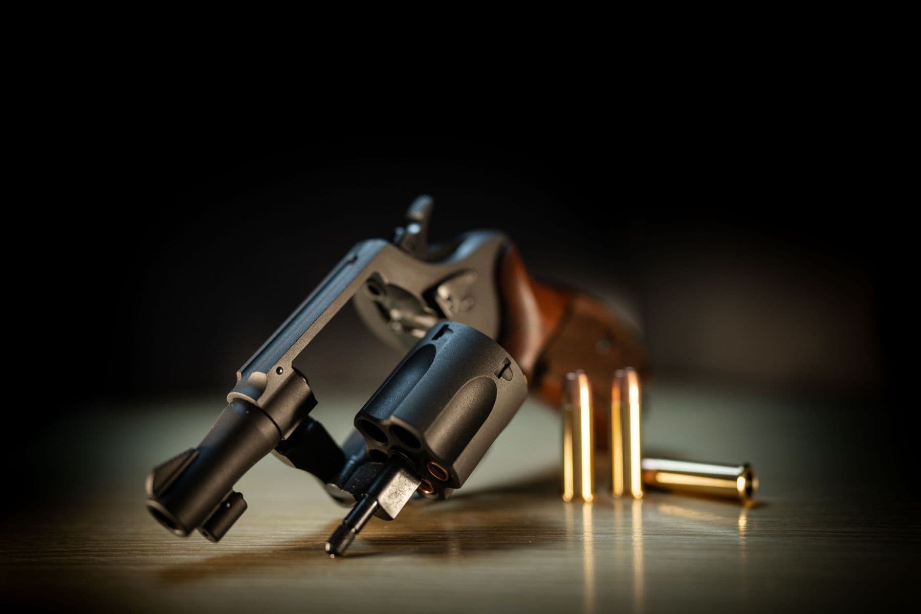 A revolver with its cylinder swung open, lit from one side