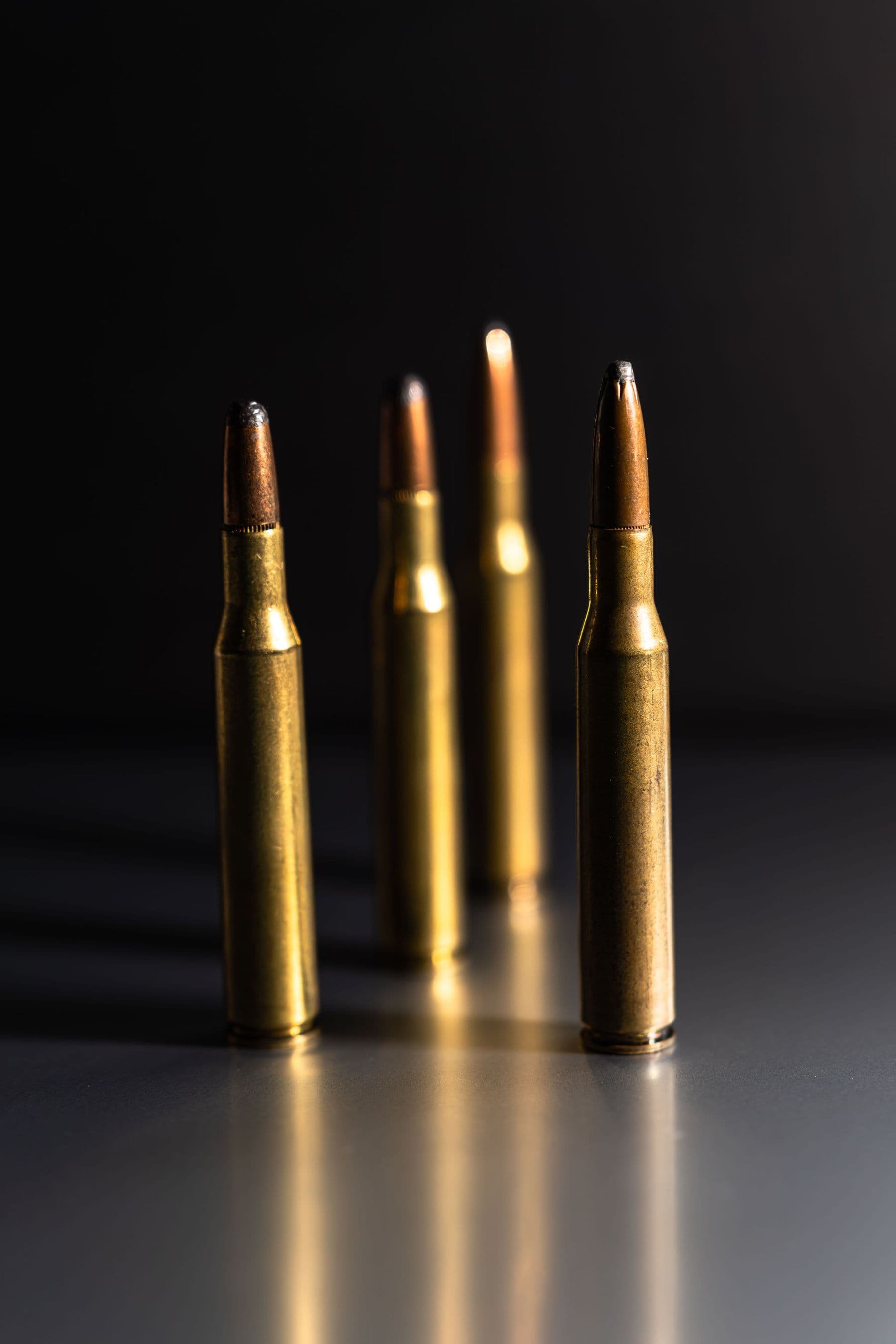 Four rifle cartridges standing on a reflective surface